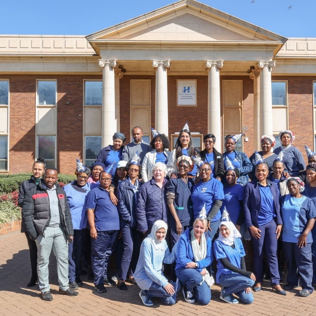 AHC Nursing College Campus AHC Nursing College students in blue uniforms posing in front of a white building with tall columns.