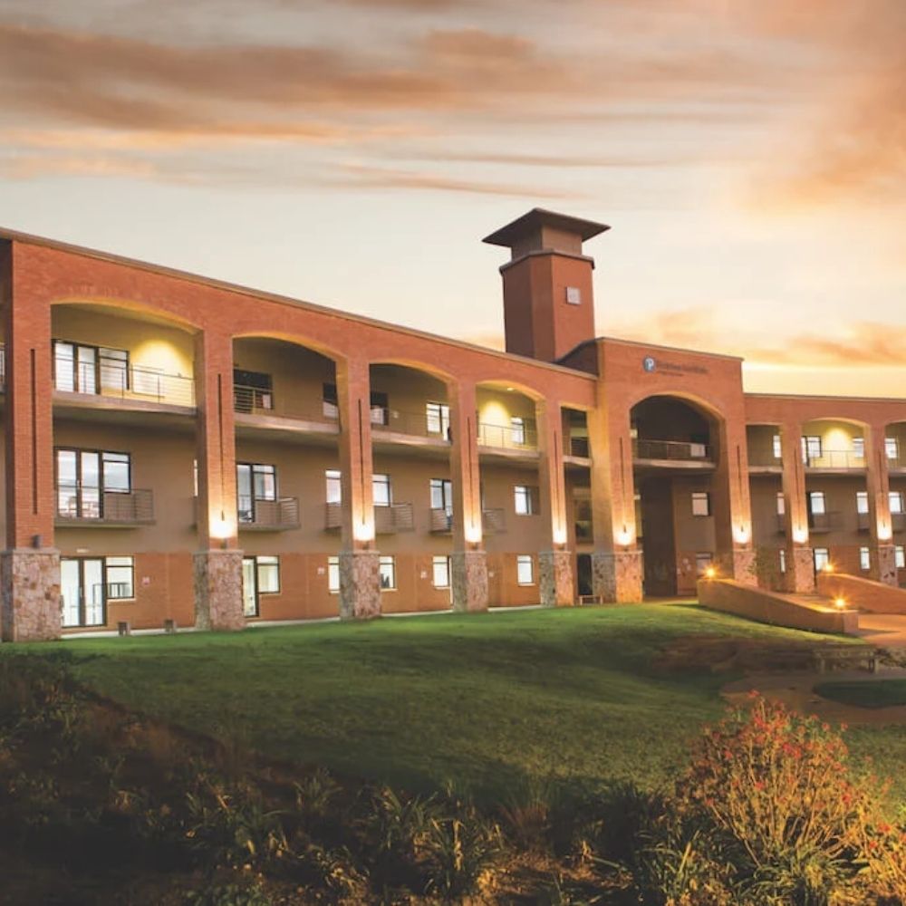 Eduvos Campus Building at Sunset Eduvos campus building with brick archways and a clock tower, illuminated warmly at sunset.