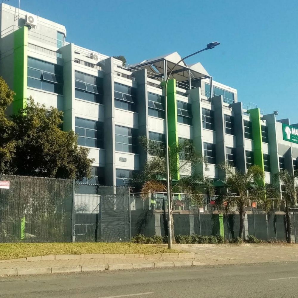 MANCOSA Campus Building Exterior MANCOSA multi story campus building exterior with green accent panels and palm trees along the street.