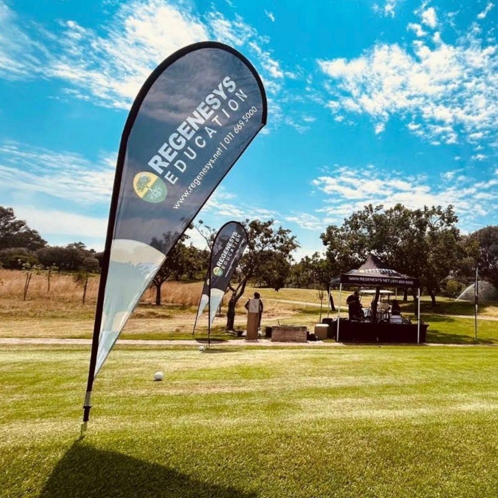 Regenesys Business School Golf Day Event Regenesys Business School branded flags and a tent set up on a golf course during a golf day event.