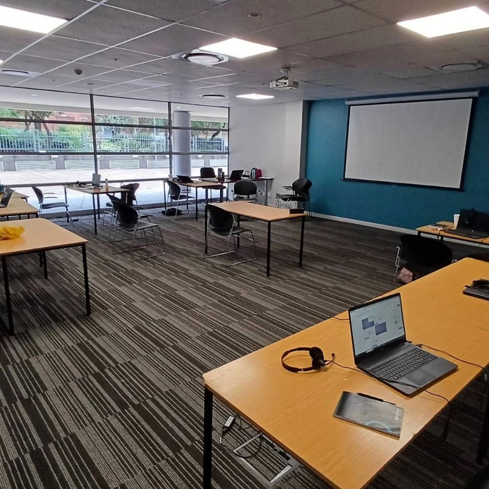 Regenesys Business School Training Classroom An empty training classroom at Regenesys Business School with desks, laptops, and a projector screen.
